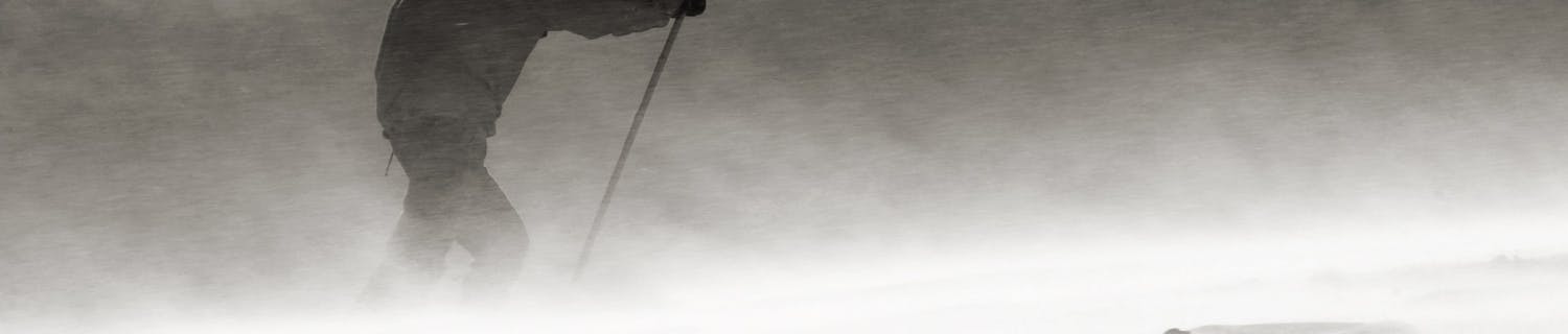 Vuorikiipeilijä kuvattuna vaeltamassa kovassa tuulessa ja lumisateessa